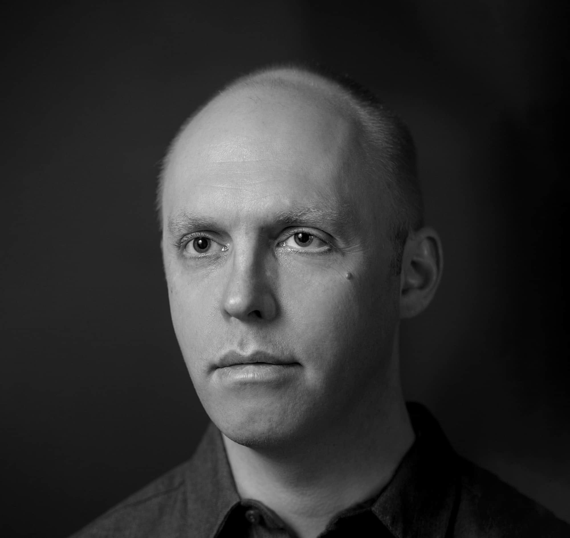 Black and white portrait (headshot) of Adam Davies.