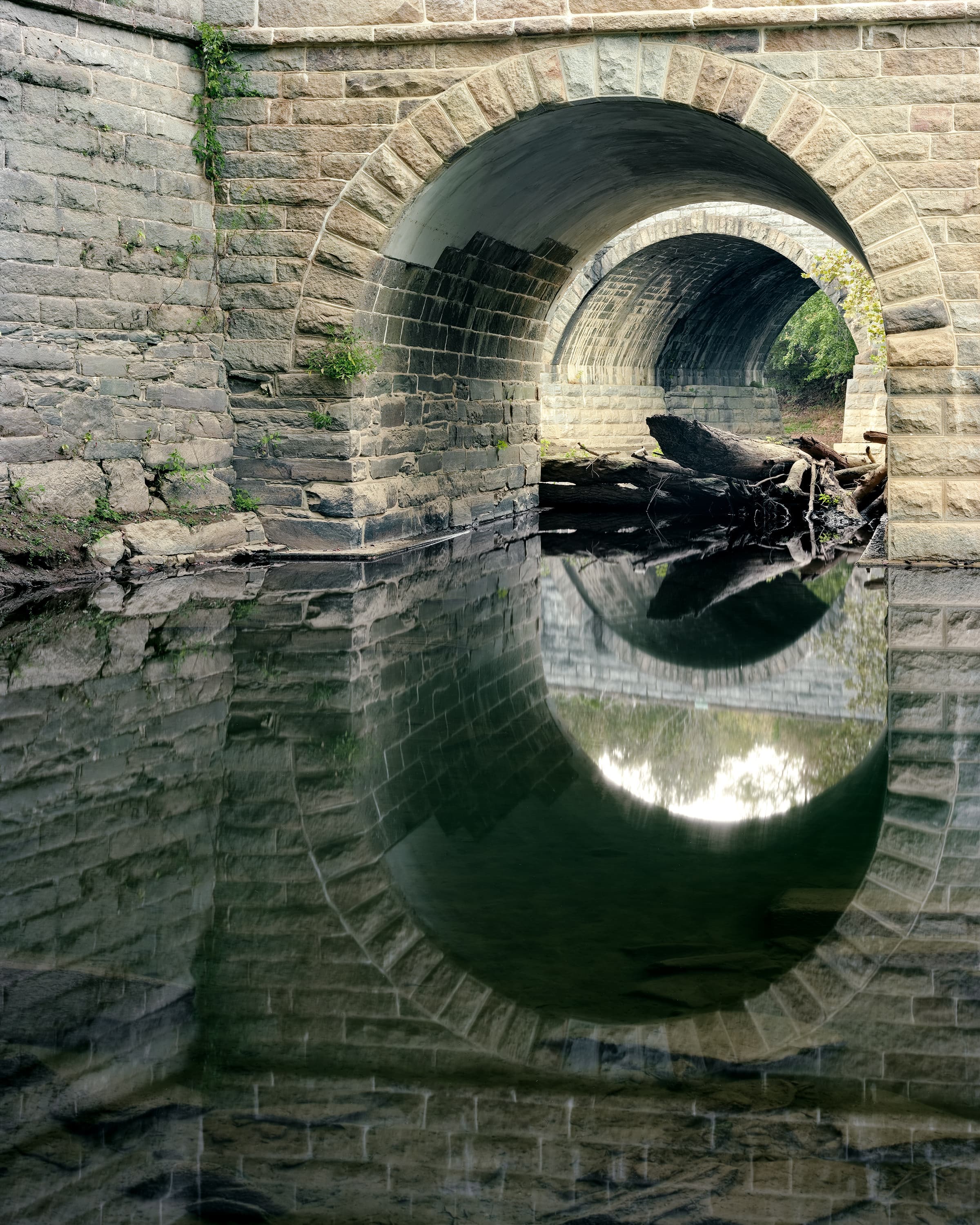 A creek crossed by two stone bridges the first an aqueduct for the C & O Canal, the second is a railway bridge for the B & O Railway.