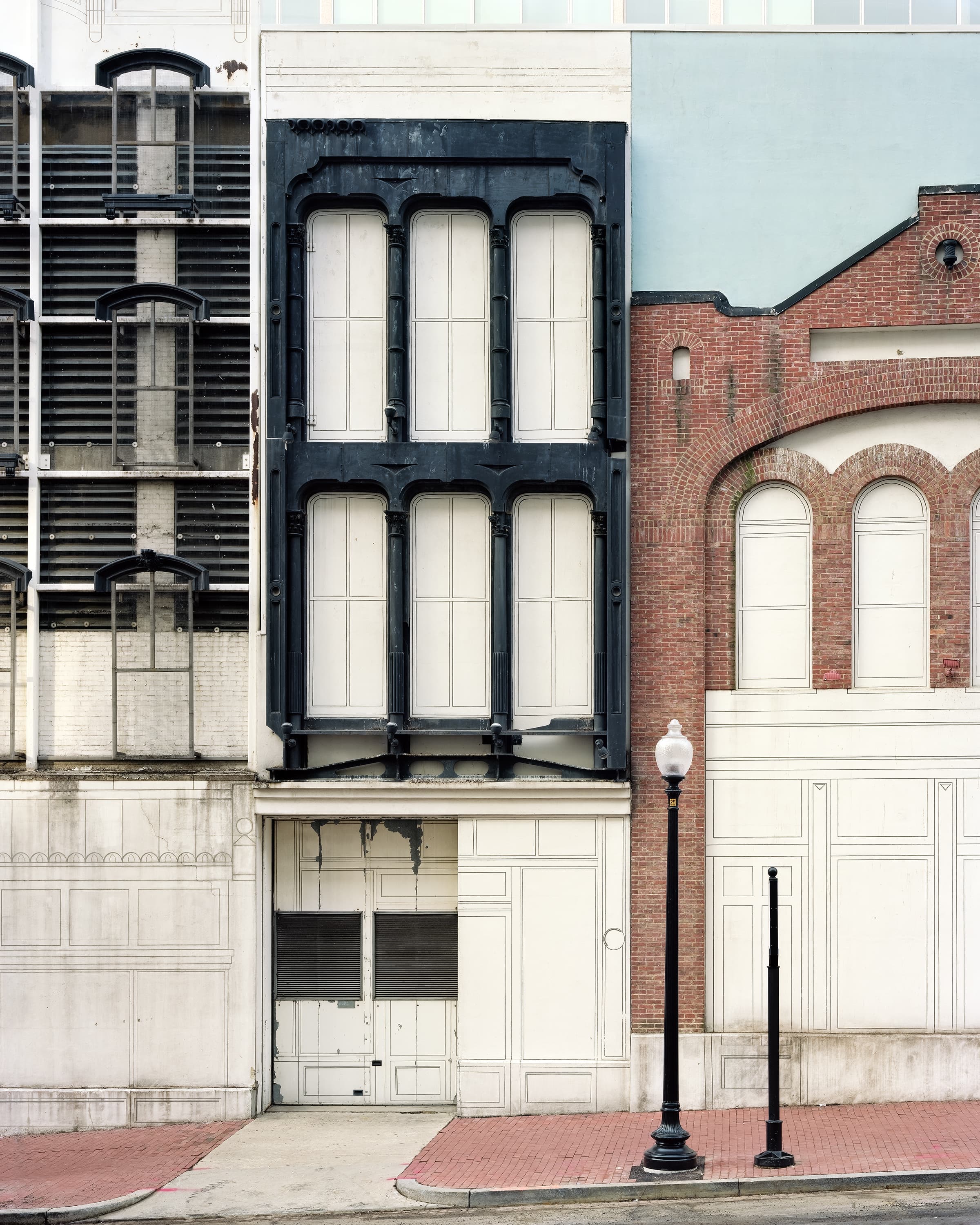 Surface of an industrial building that has been decorated with line art and a false sky to attempt to match surrounding historic architecture.