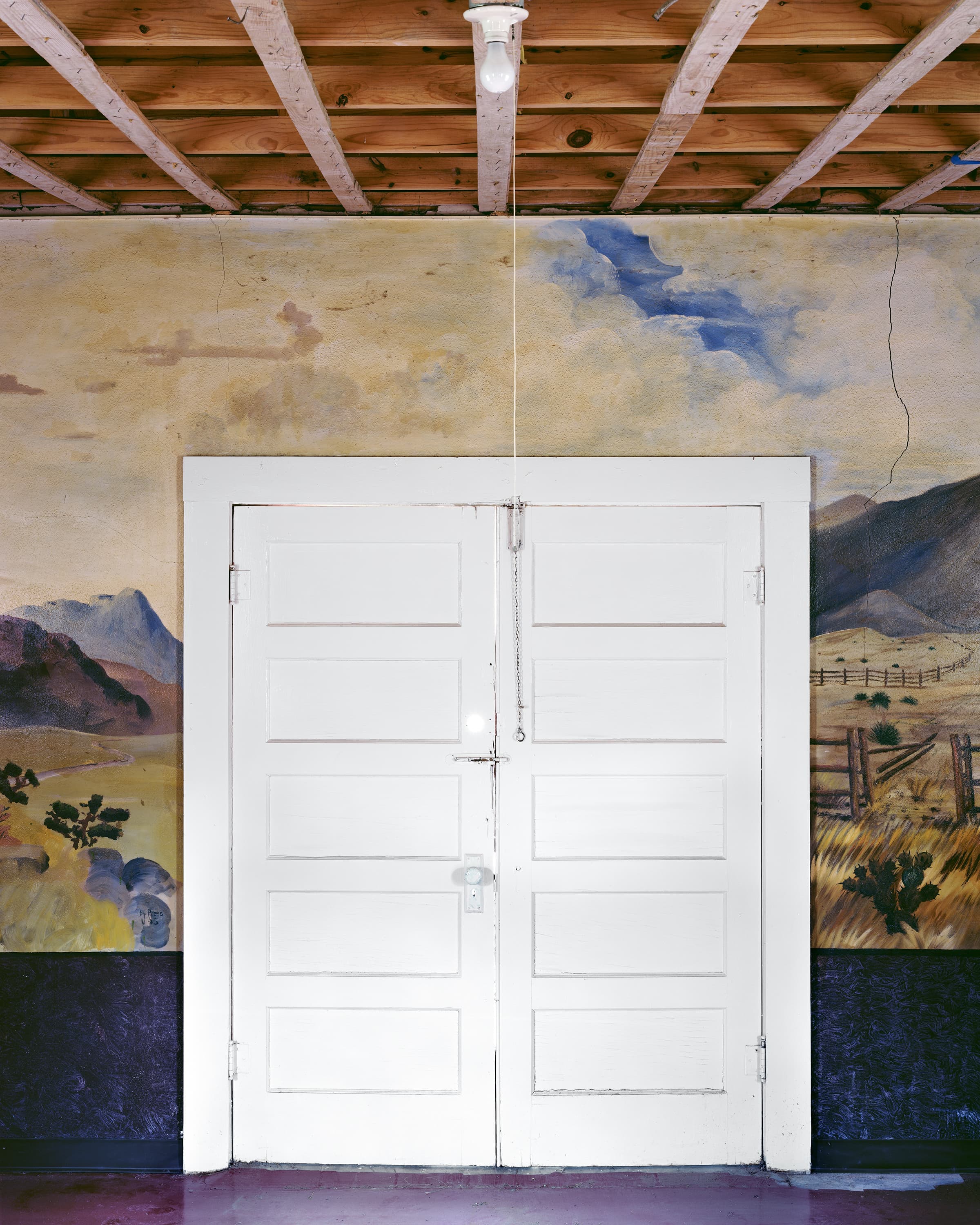 Landscape painted by German WWII prisoners-of-war painted on the interior of United States military barracks, surounding a door to the outside.