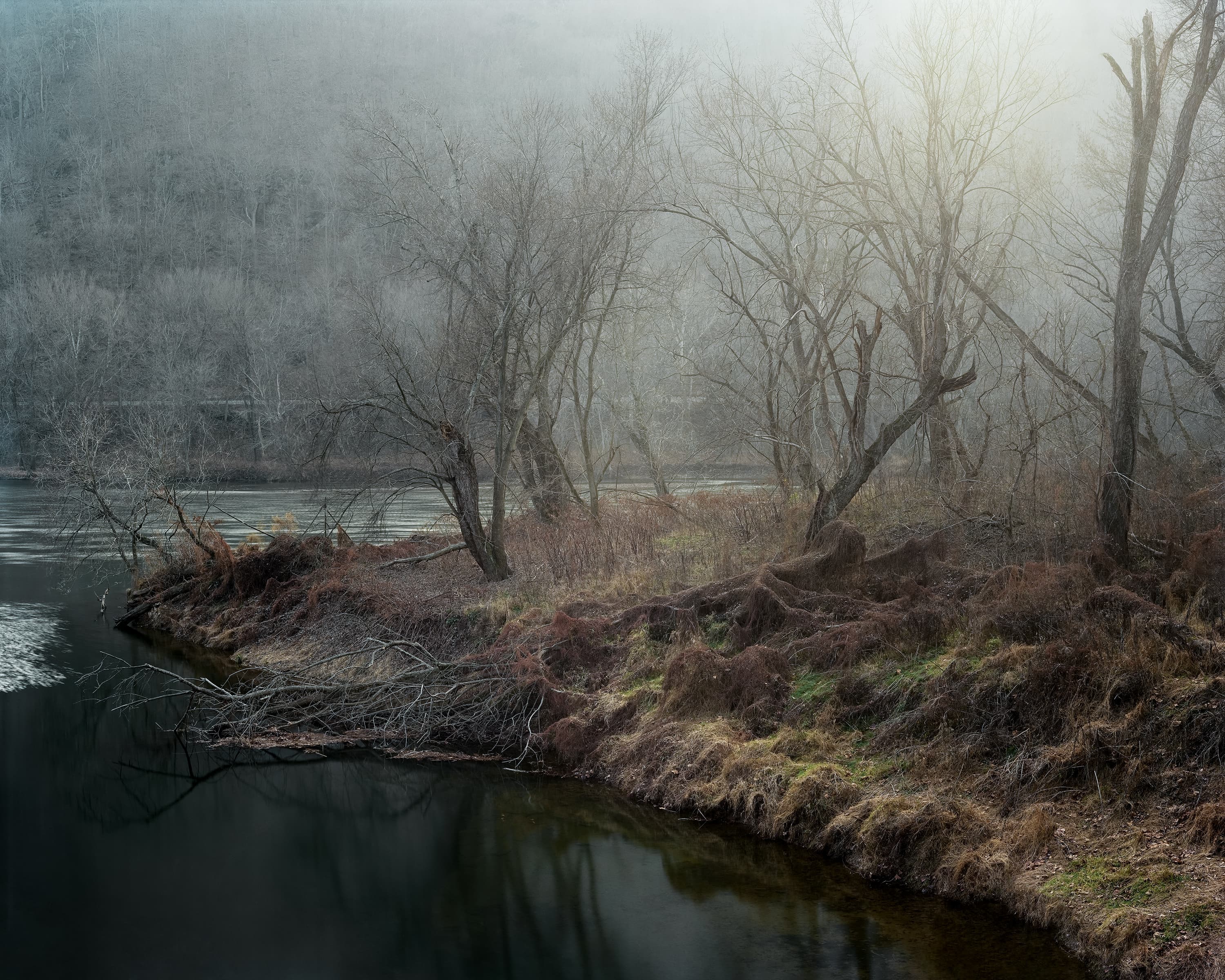 Looking across the Potomac river to cliffs and a railway covered in fog.