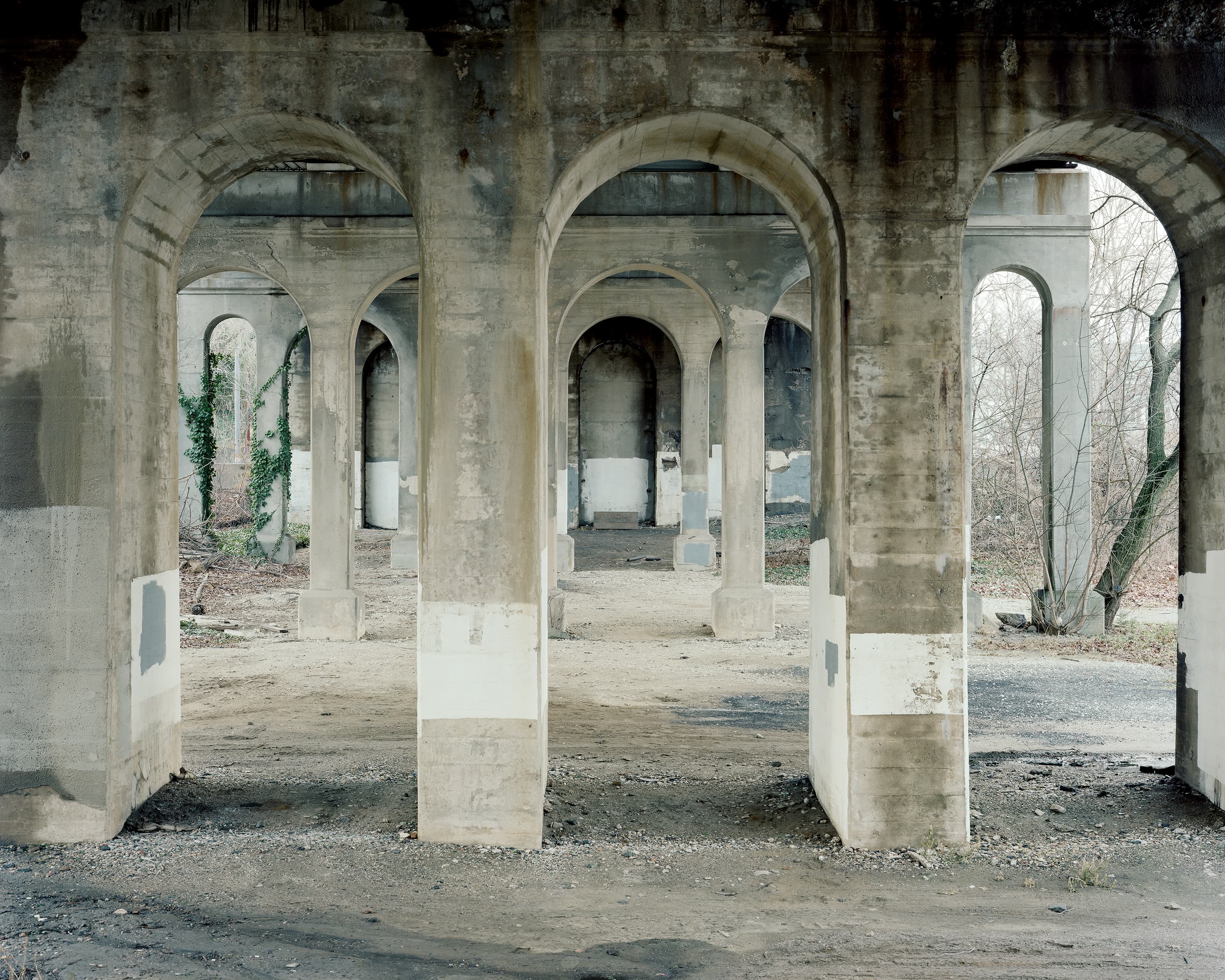 Underneath an arched railway bridge in Baltimore, piers are whitewashed to cover graffiti.