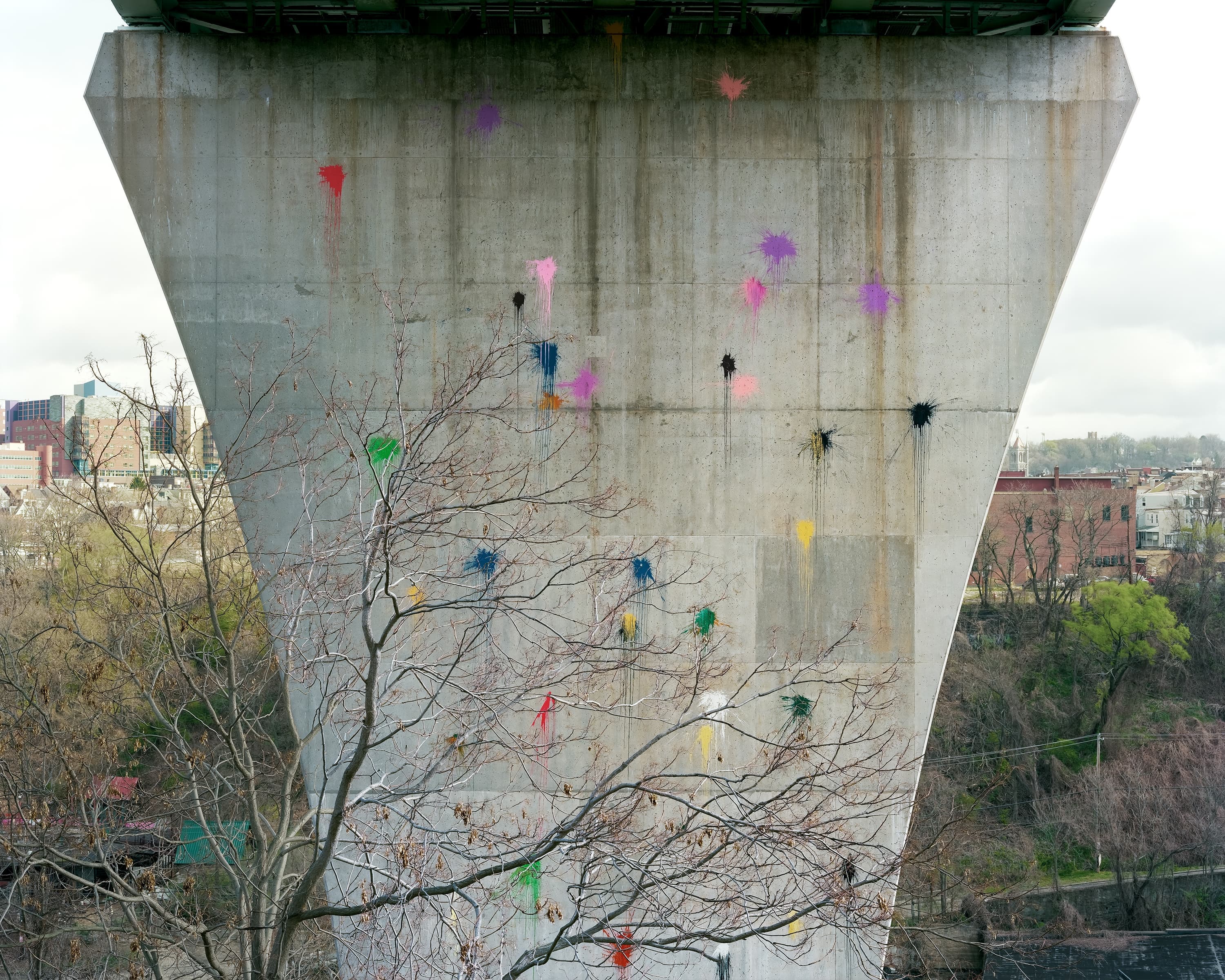 Multi-colored paint splattered on the pier of the bridge.